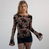 Woman wearing a sheer long-sleeve top with black floral pattern